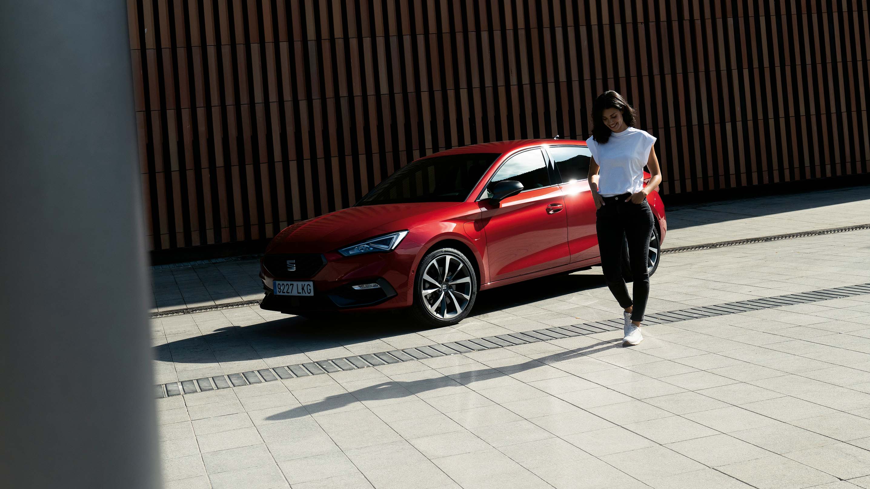 Hybrid vehicle seat leon in red parked in the shadows by a building